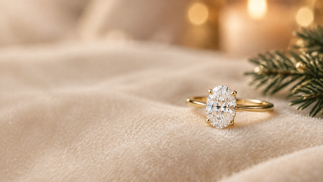 An oval diamond engagement ring in yellow gold on soft ivory fabric, with a subtle evergreen detail